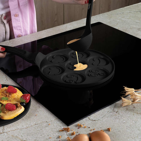 Product image of 7holes emoji pancake pan 26cm. Part of the Matte Black Collection/Black Rose Collection . Features: • Material: cast aluminium • Pancake pan Ø26*1,3 cm • Color: matt black. (Studio view). Official Berlinger Haus product, boosted by Promintra sl.