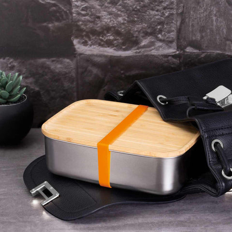 Product image of Lunch box with bamboo lid. Part of the kitchen accessories . Features: • Material: 18/10 stainless steel, bamboo • Size: 21,2*15,8*7 cm • Capacity: 1500 ml • 2 in 1: bamboo lid and cutting board • Silicone elastic strap. (Studio view). Official Berlinger Haus product, boosted by Promintra sl.